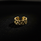 Gold infinity knot weave open cuff ring on black velvet with dramatic rim lighting