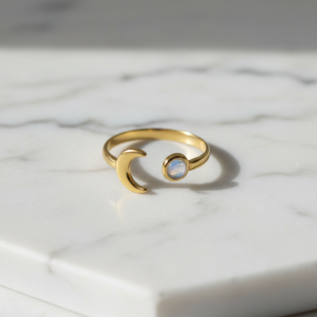 Gold moon and moonstone open band ring on white marble surface