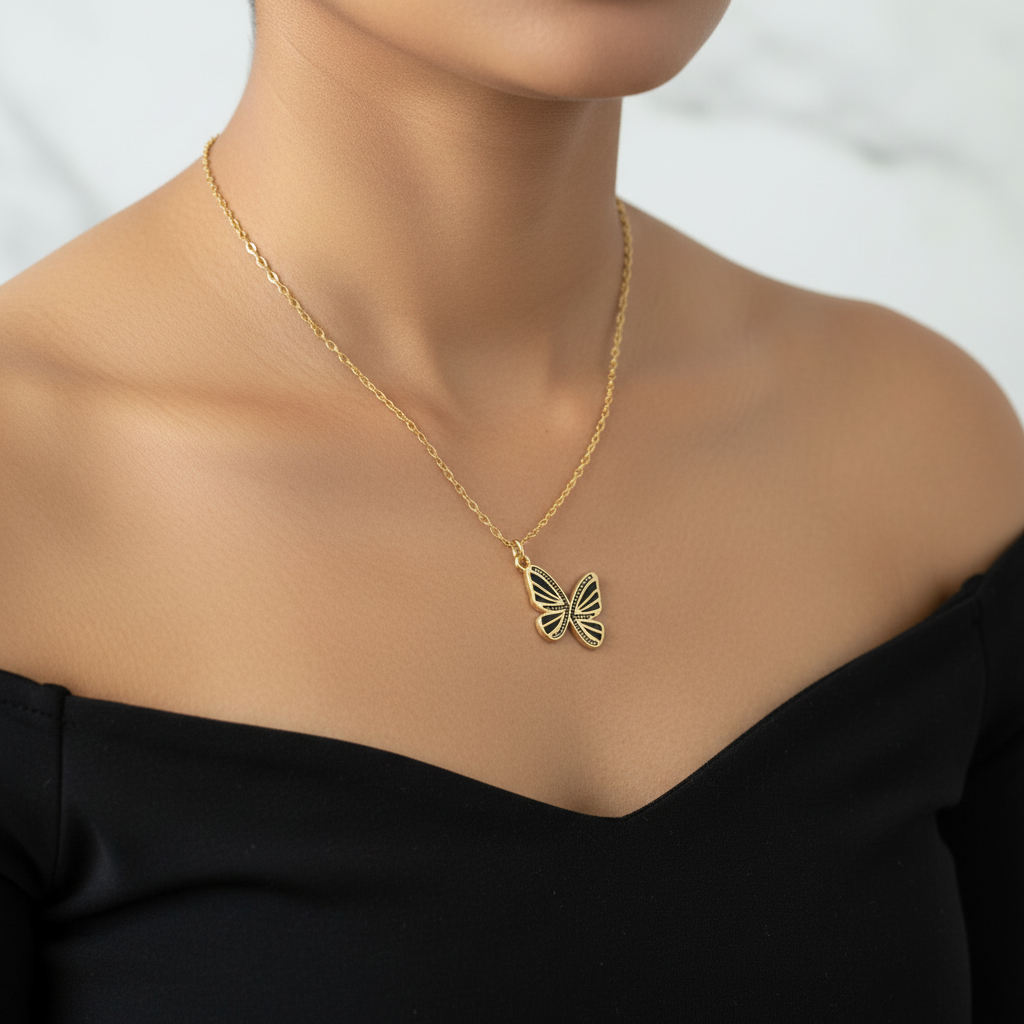 Model wearing black enamel butterfly pendant necklace on gold cable chain with single-wing attachment for natural tilt
