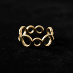 Gold open circle link band open cuff ring on black velvet with dramatic rim lighting