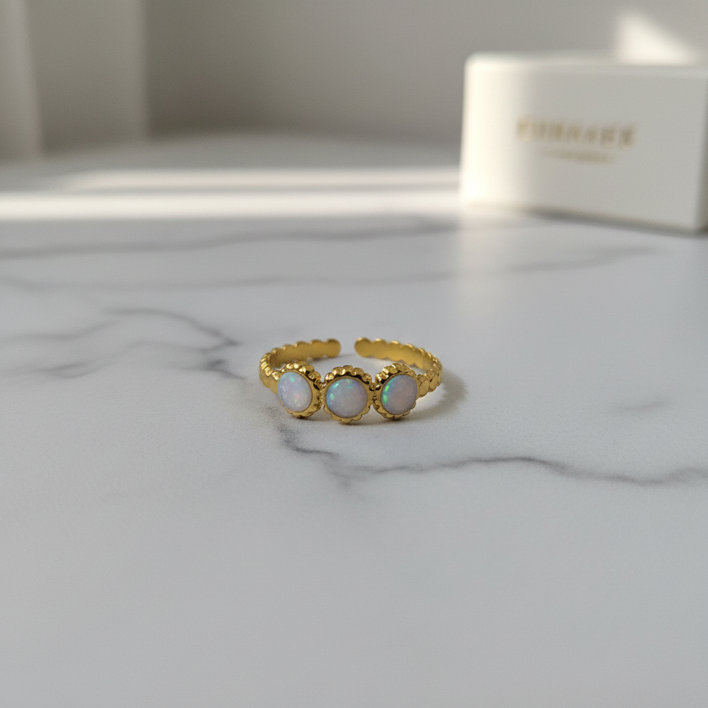 Gold triple moon phase opal ring on white marble surface