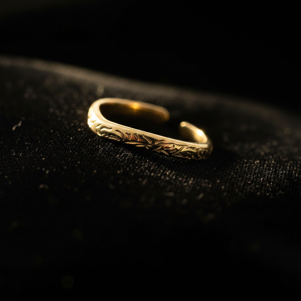 Gold engraved floral band open cuff ring on black velvet with dramatic rim lighting