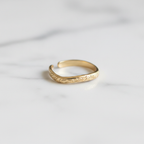 Gold engraved floral band open cuff ring on white marble surface