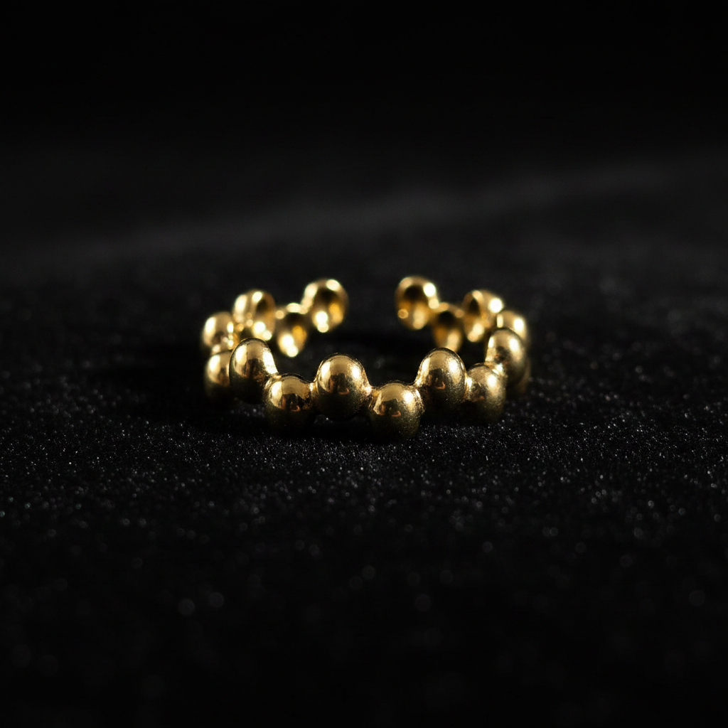Gold beaded bubble band open cuff ring on black velvet with dramatic rim lighting