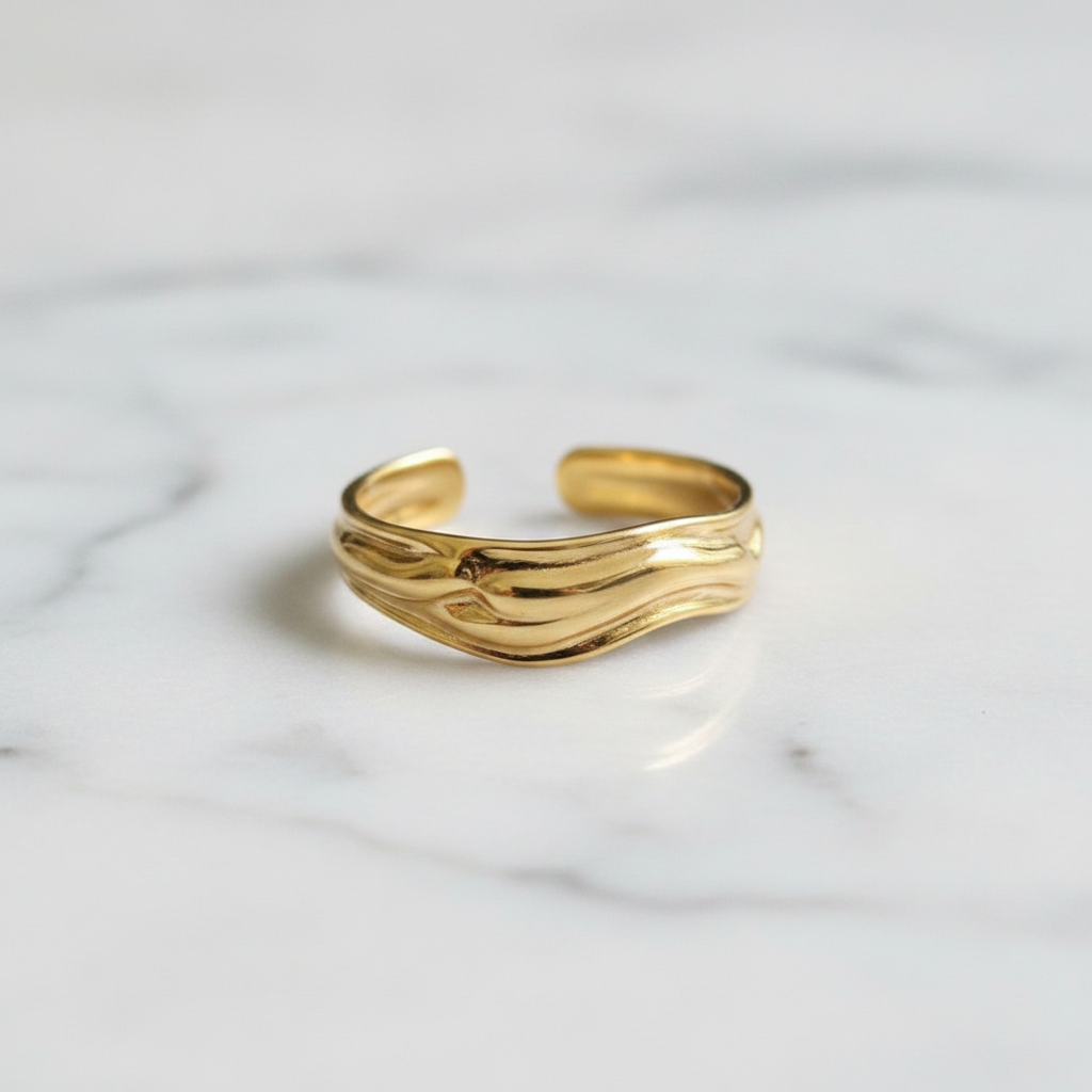 Gold molten wave sculptural open cuff ring on white marble surface