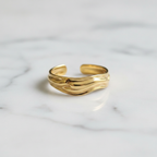 Gold molten wave sculptural open cuff ring on white marble surface
