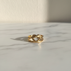 Gold heart cutout open cuff ring on white marble surface