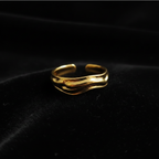 Gold molten wave sculptural open cuff ring on black velvet with dramatic rim lighting