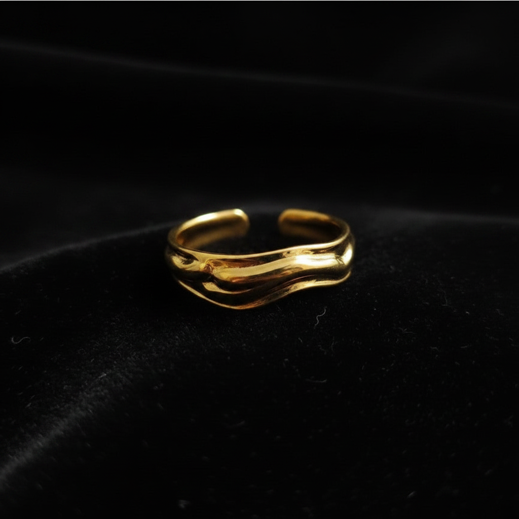 Gold molten wave sculptural open cuff ring on black velvet with dramatic rim lighting