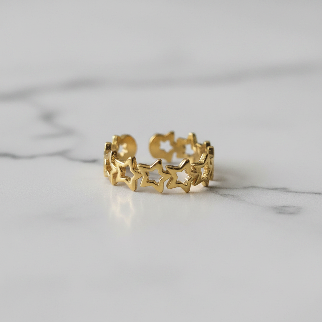Gold linked star cutout band open cuff ring on white marble surface