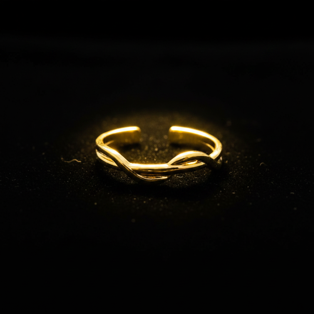 Gold twisted braided band open cuff ring on black velvet with dramatic rim lighting