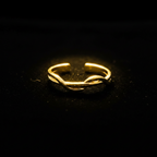 Gold twisted braided band open cuff ring on black velvet with dramatic rim lighting