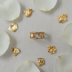 Gold diamond cutout lace crown ring flat lay with white rose petals and gold foil
