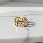 Gold diamond cutout lace crown ring on white marble surface