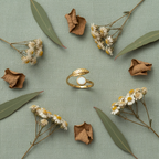 Gold leaf and white stone bypass open cuff ring on sage green linen with dried leaves and wildflowers