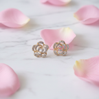 Styled flat-lay shot of Violet Vows gold rose stud earrings with pavé crystals surrounded by pink petals on marble.