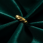 Gold twisted croissant ring on emerald green velvet fabric