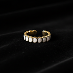 Gold white oval enamel wide band open cuff ring on black velvet with dramatic lighting