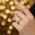 Gold twisted braided band open cuff ring worn on finger with warm golden bokeh