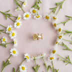 Gold flower bloom open cuff ring flat lay on blush pink fabric with white flowers