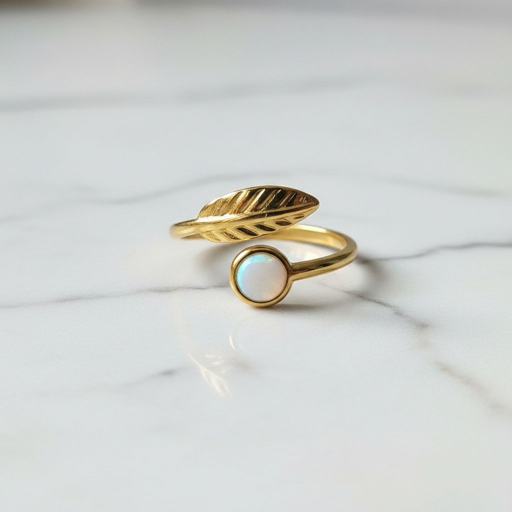 Gold leaf and white stone bypass open cuff ring on white marble surface