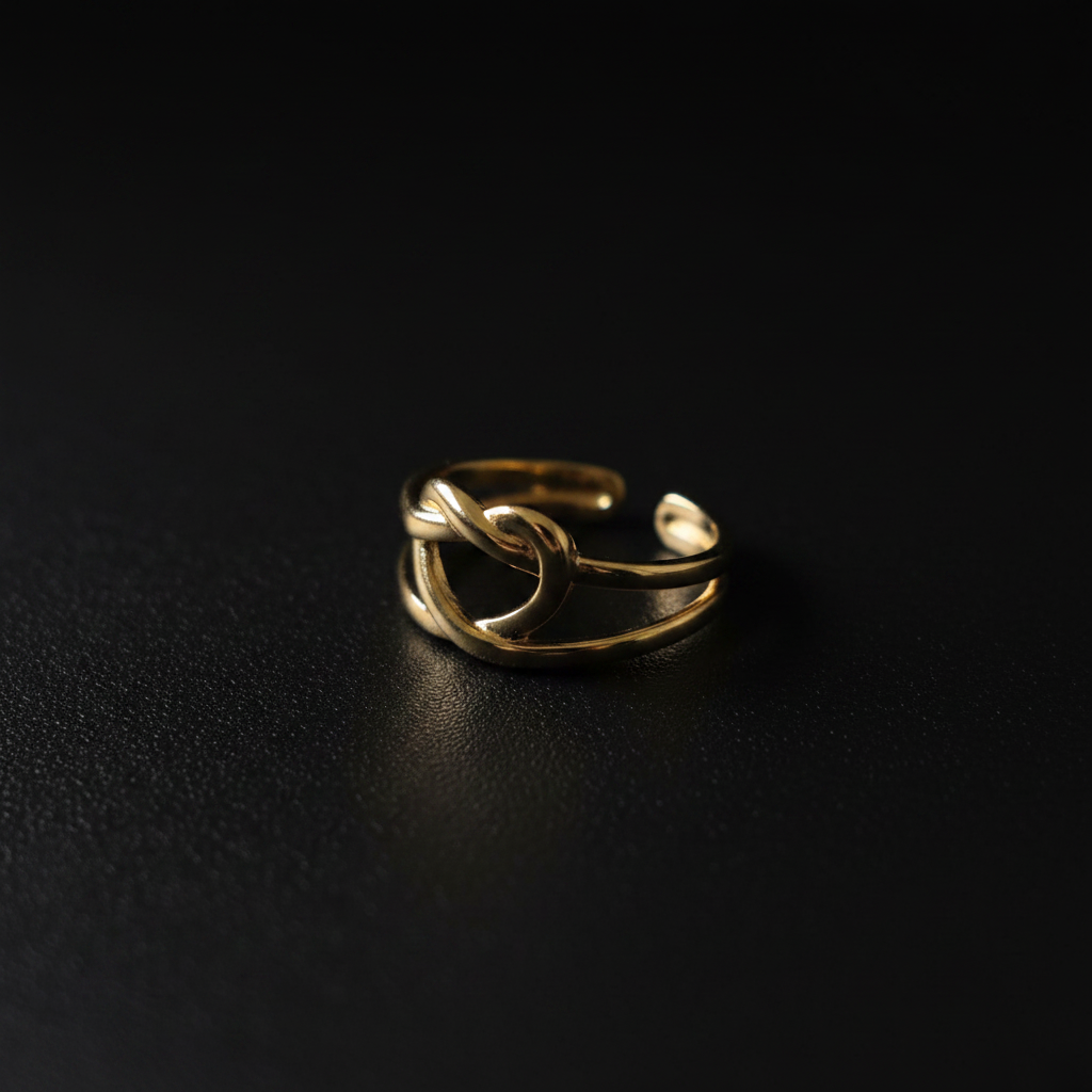 Gold heart cutout open cuff ring on dark matte surface with dramatic lighting