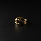 Gold heart cutout open cuff ring on dark matte surface with dramatic lighting