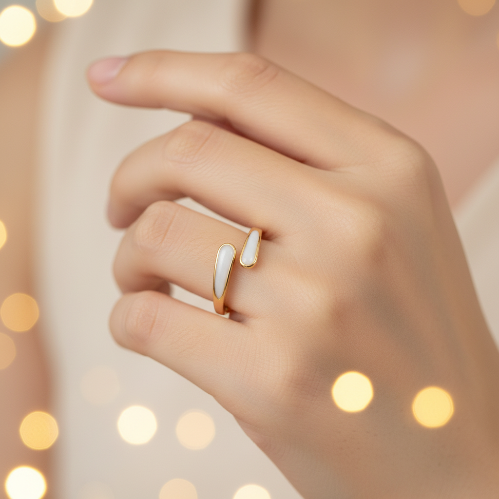 Gold and white stone bypass open cuff ring worn on finger with warm golden bokeh