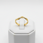 Gold twisted braided band open cuff ring on white jewelry stand, clean studio shot
