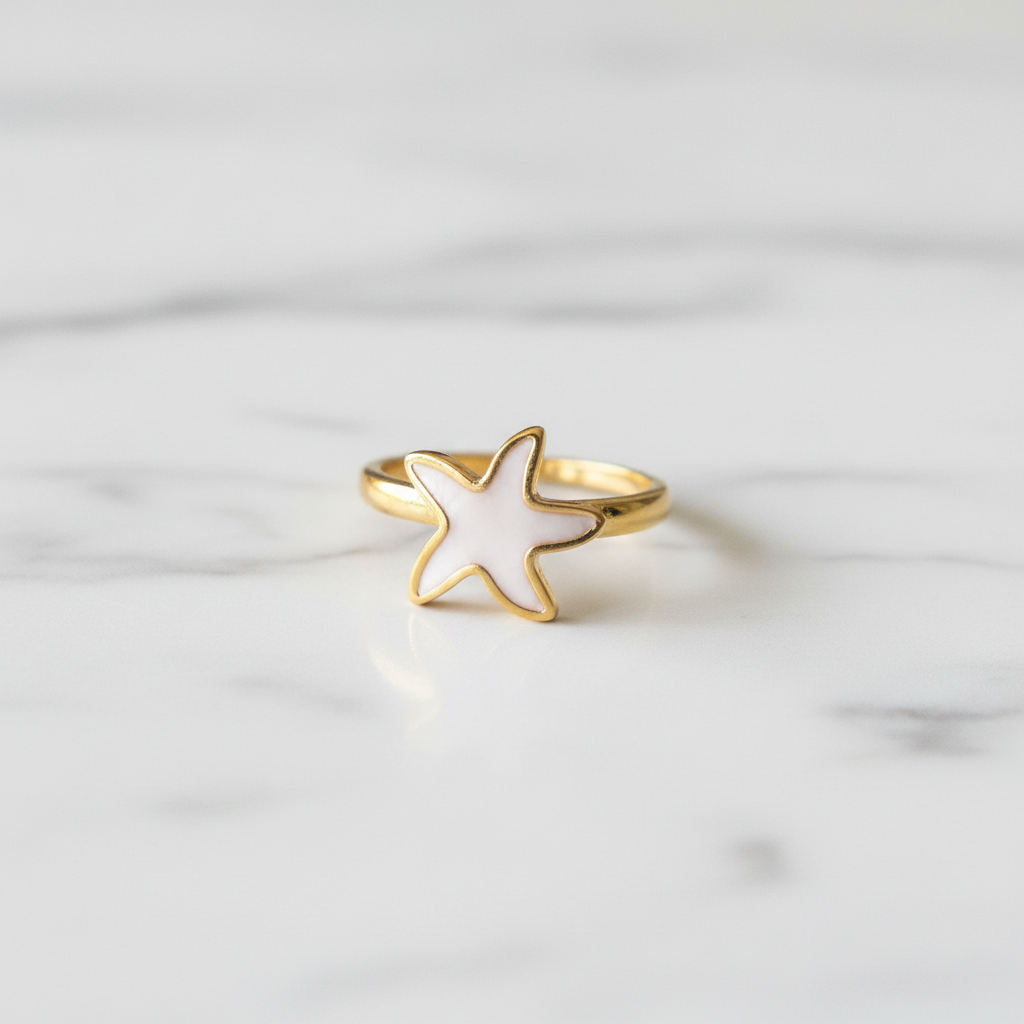 Gold white enamel starfish open cuff ring on white marble surface