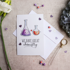 Flat lay composition of chemistry greeting card with envelope and science-themed decorative elements