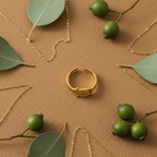 Gold belt buckle braided chain open cuff ring on tan leather with gold chain links and eucalyptus