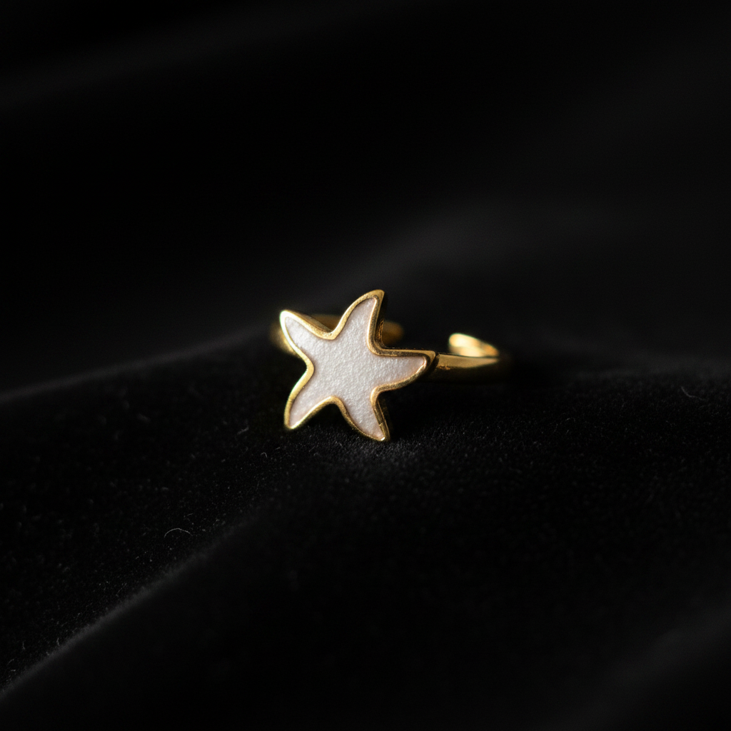 Gold white enamel starfish open cuff ring on black velvet with dramatic rim lighting