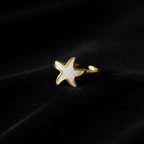 Gold white enamel starfish open cuff ring on black velvet with dramatic rim lighting