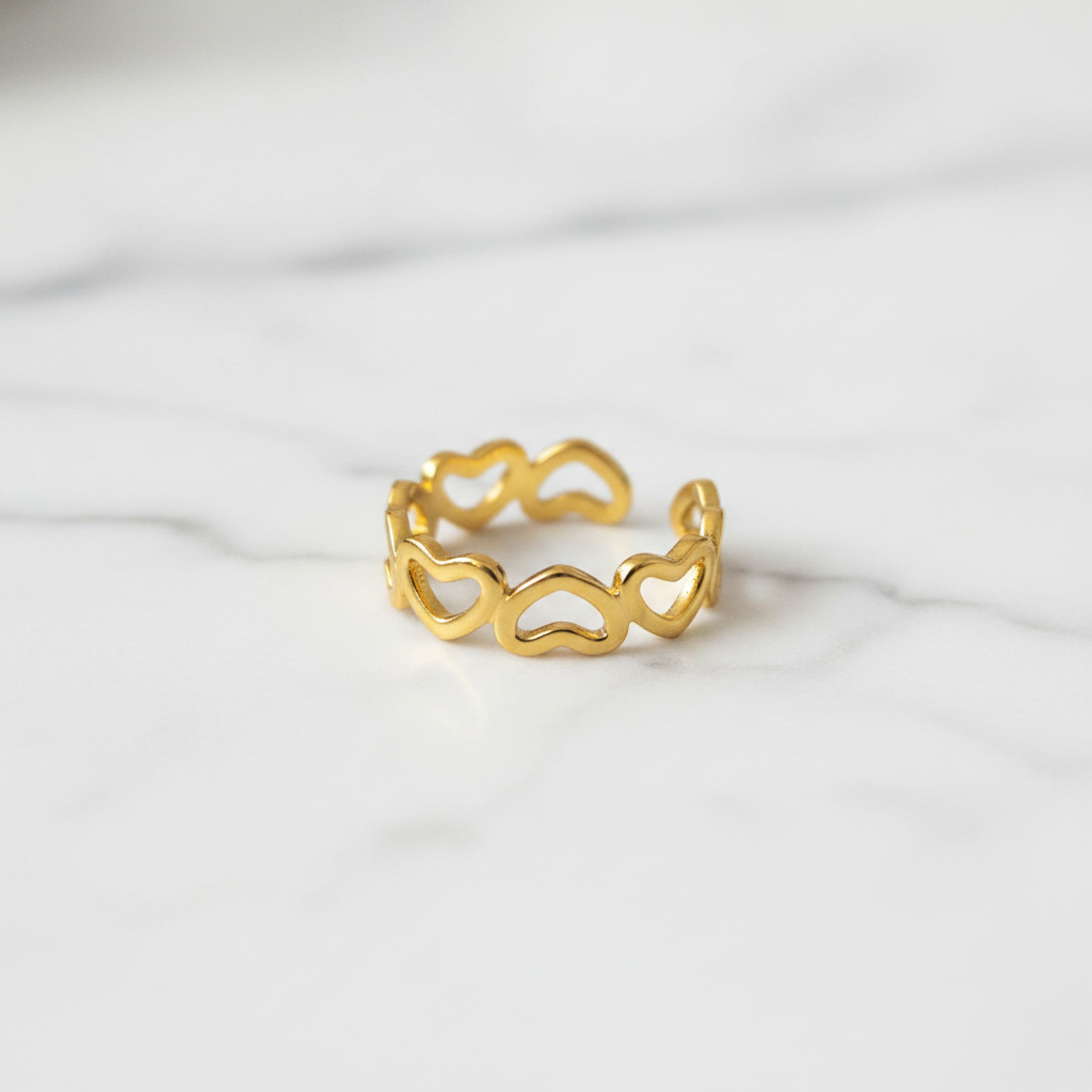 Gold open heart cutout band open cuff ring on white marble surface