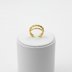 Gold double band twisted rope and plain open cuff ring on white jewelry stand, clean studio shot