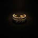 Gold feather engraved open cuff ring on black velvet with dramatic rim lighting