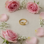 Gold hug ring flat lay with pink rose petals and baby's breath flowers