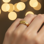 Gold molten wave sculptural open cuff ring worn on finger with warm golden bokeh
